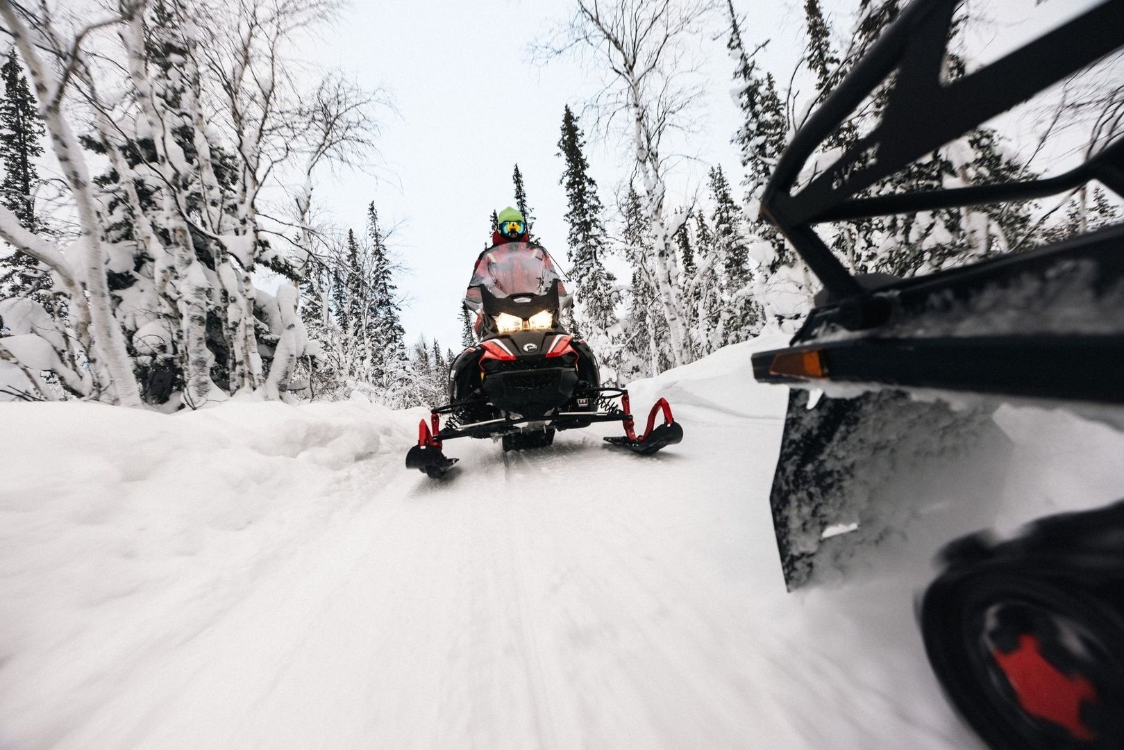 Snowmobile rider traveling through deep powder on a snowy forest trail